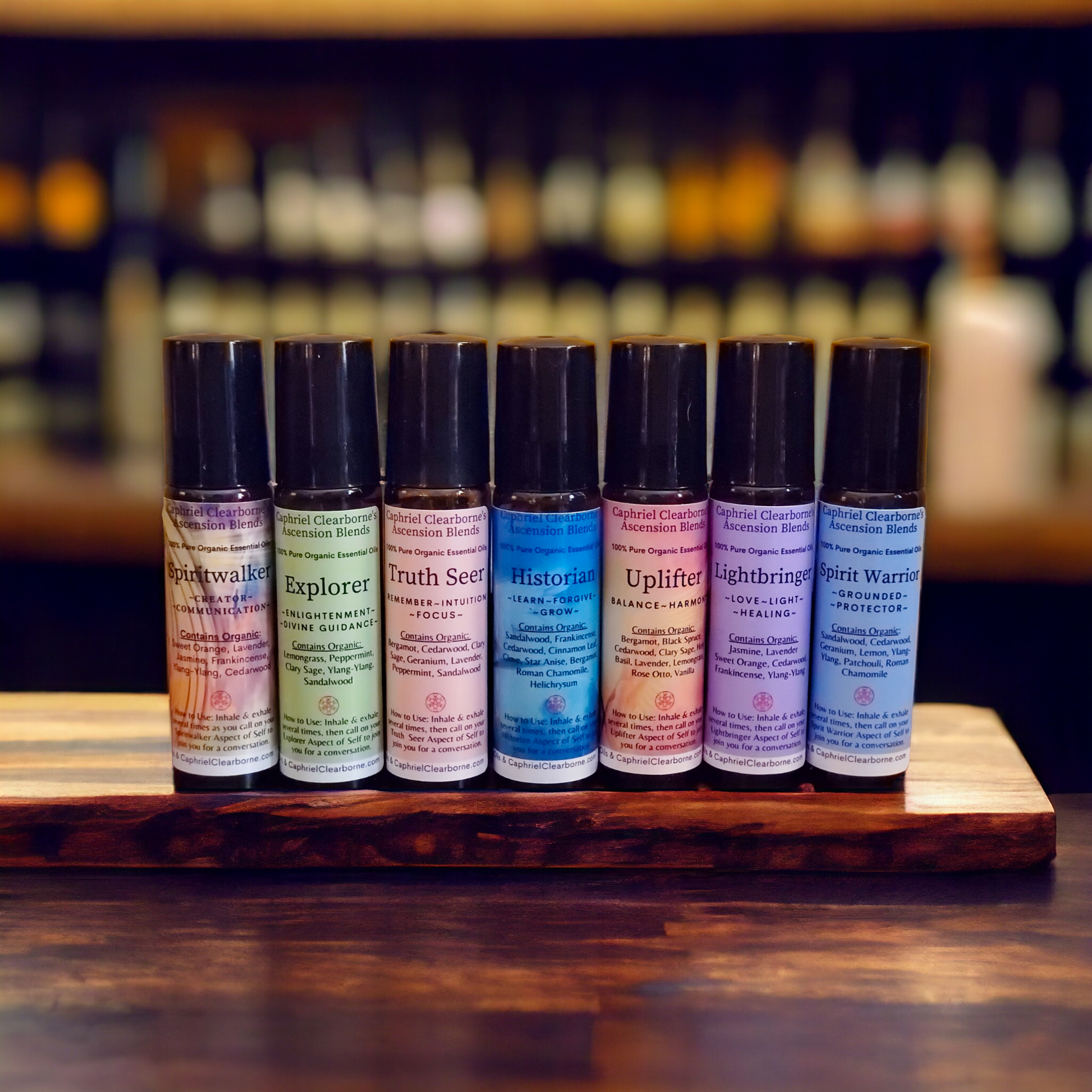 Ascension Blends for spiritual growth in 10ml roller bottles, showcasing the complete collection including Spiritwalker, Explorer, Truth Seer, Historian, Uplifter, Lightbringer, and Spirit Warrior, meticulously aligned on a wooden platform against a backdrop of shelves stocked with diverse essential oils.