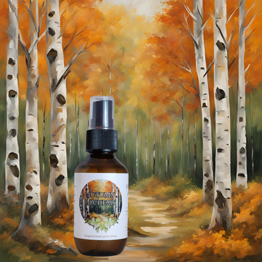 An Autumn Alchemy spray bottle is placed in front of a scenic autumn forest backdrop. The background features vibrant orange and yellow leaves on birch trees lining a path, capturing the essence of fall. The spray bottle is labeled with the product name and a logo, emphasizing its natural and seasonal fragrance.