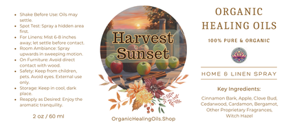 Harvest Sunset Spray "Label for Harvest Sunset Home & Linen Spray by Organic Healing Oils. The label features an autumn scene with apples and cinnamon sticks on a table at sunset. Instructions for use are on the left. The product is described as 100% pure and organic, highlighting key ingredients like cinnamon bark, apple, clove bud, cedarwood, cardamom, bergamot, other proprietary fragrances, and witch hazel."