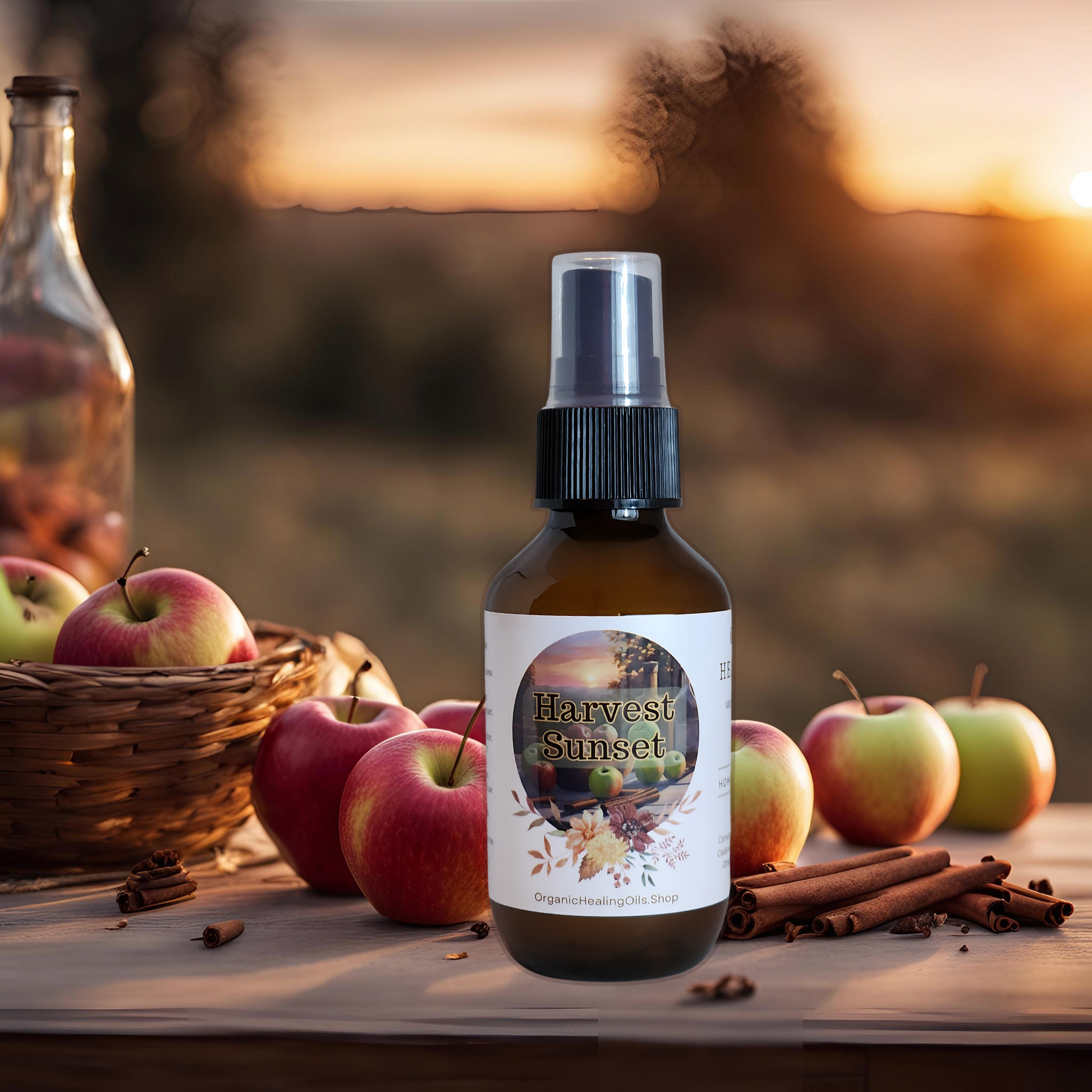 Harvest Sunset spray bottle by Organic Healing Oils, on a wooden table with apples spilling out of a basket and cinnamon sticks scattered around. The background features an apple orchard and a beautiful sunset, creating a cozy harvest ambiance.